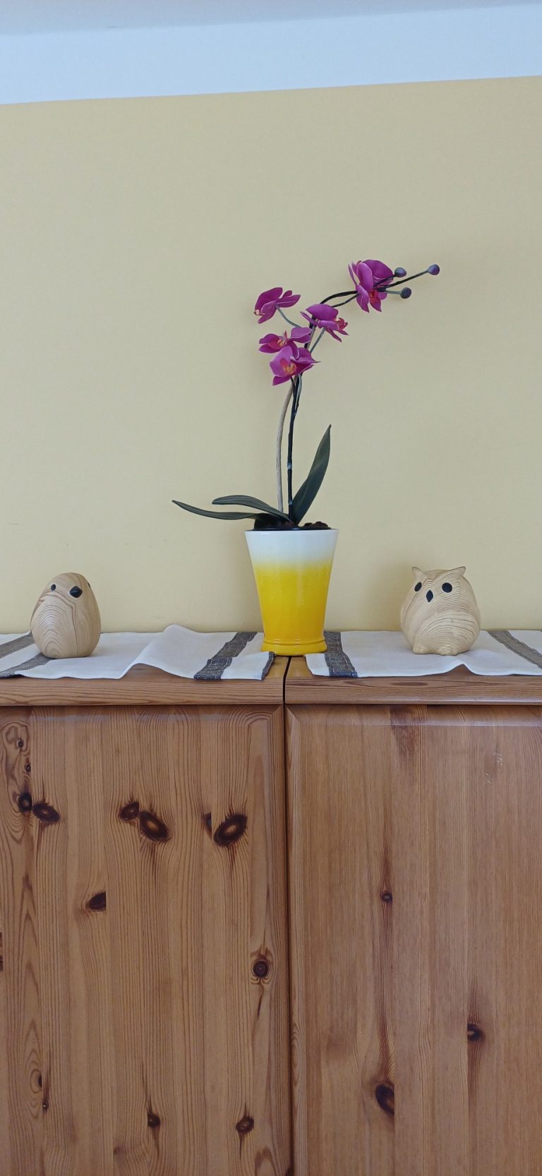 Gemütliche Details zum Wohlfühlen
Liebevolle Dekoration aus Holzfiguren und Orchidee auf Holzkommode.