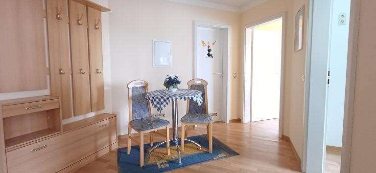 Diele und Sitzbereich – Gästehaus am Weinberg Eingangsbereich der Ferienwohnung mit einem kleinen Tisch und zwei Stühlen.