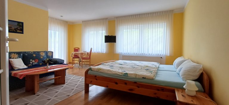 Schlafzimmer– Gästehaus am Weinberg Sinsheim Gemütliches Schlafzimmer mit Doppelbett aus Holz, Parkettboden und hellen Fenstern.