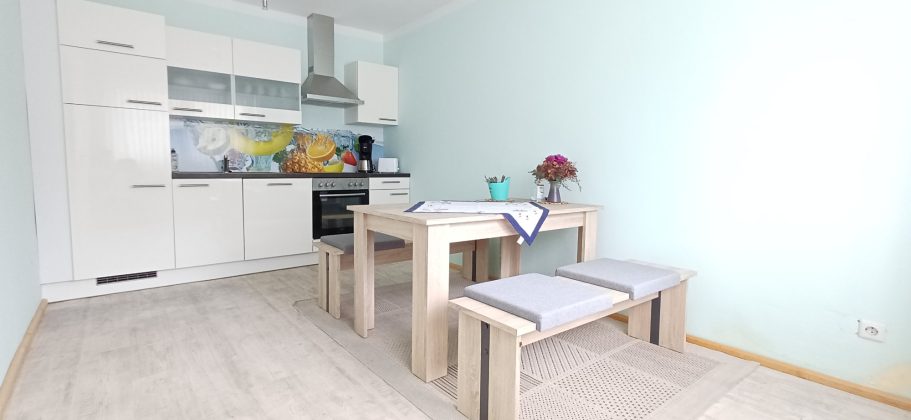 Gemeinschaftsküche Küche mit Holztisch, Bänken und modernen Geräten, hellblauer Wandfarbe.