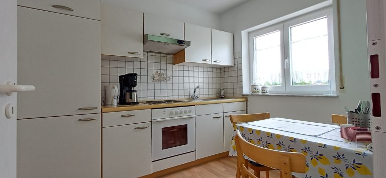 Voll ausgestattete Küche – Gästehaus am Weinberg Helle Einbauküche mit Herd, Backofen, Kaffeemaschine und Essbereich.