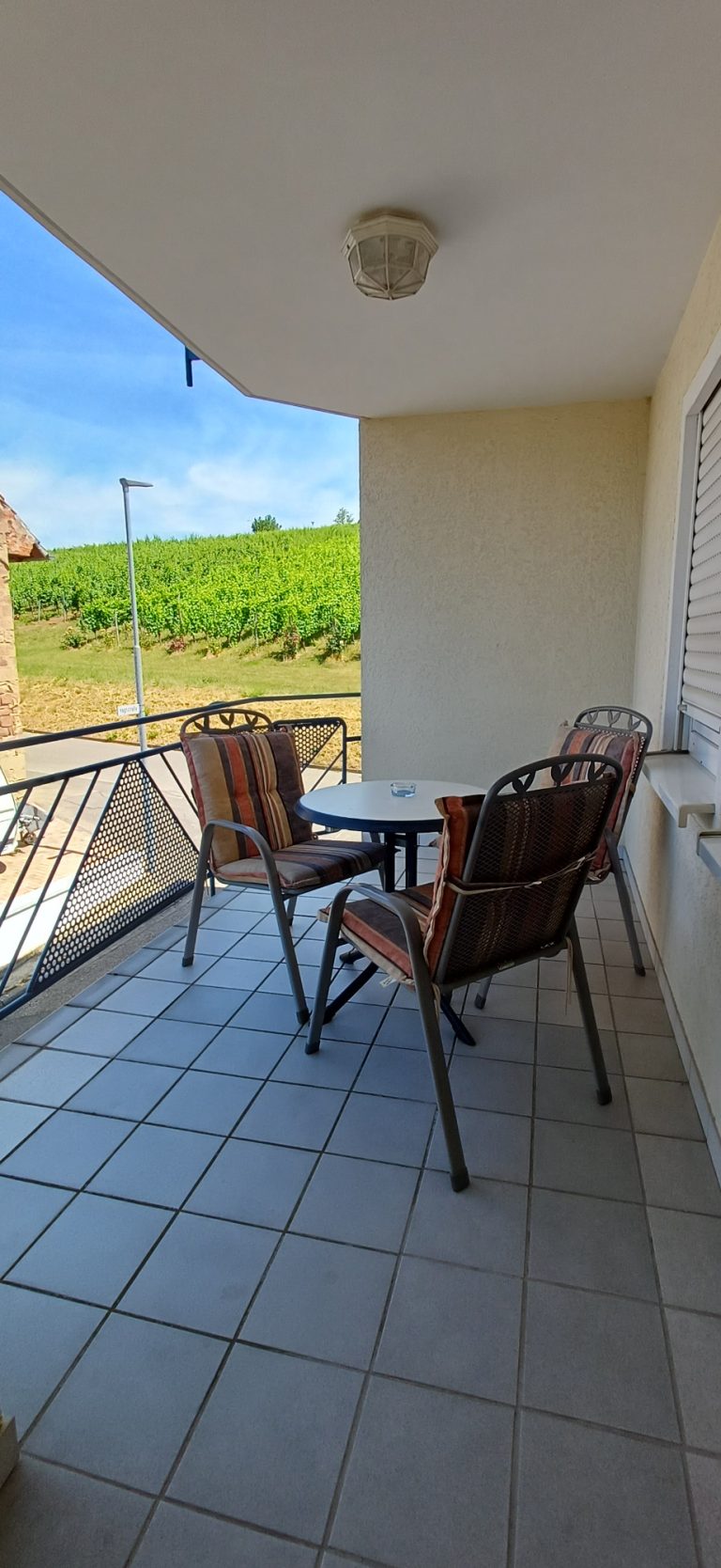 Balkon mit Aussicht – Gästehaus am Weinberg Überdachter Balkon mit Sitzgruppe und Blick auf die Weinberge von Sinsheim-Weiler.