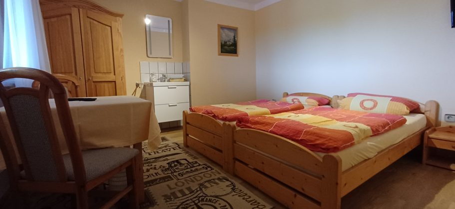Doppelzimmer Gemütliches Zimmer mit zwei Betten, Tisch und Holzschränken. Helle, einladende Atmosphäre.